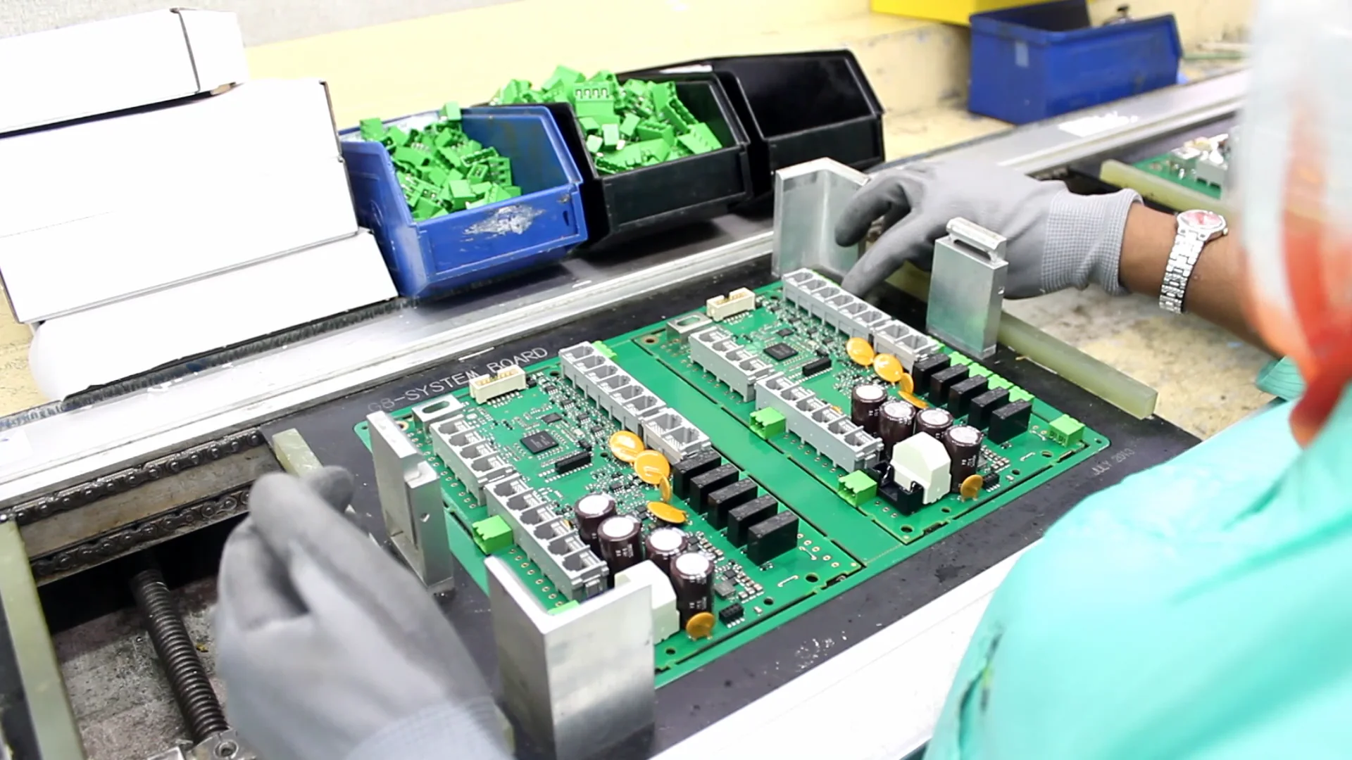 Gloved operator handling a populated circuit board at an assembly station